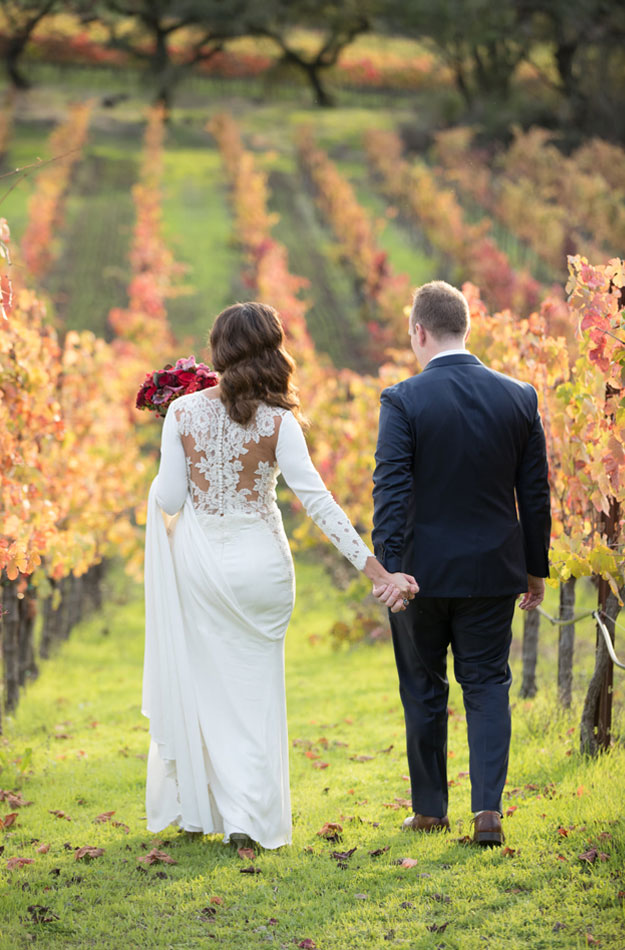Bride and groom walking hand-in-hand in the vineyard